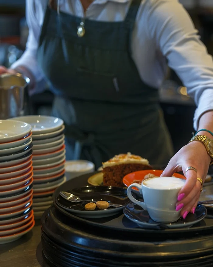 Bedienung serviert Kaffee und Kuchen am Tresen eines Cafés